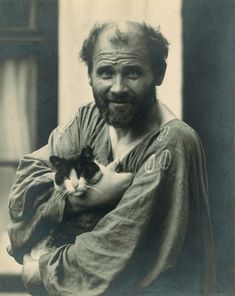 an old black and white photo of a man with a cat in his arms,