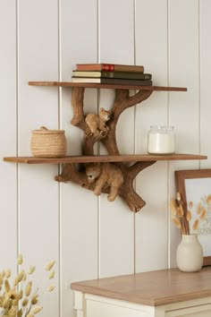 two wooden shelves with books on them in a white room next to a table and vase