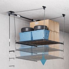 two blue containers are suspended from the ceiling by metal bars and hooks, with boxes on each shelf behind them