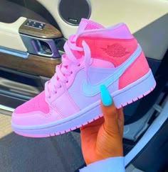 a person holding up a pink and blue nike air force sneakers in their hand,