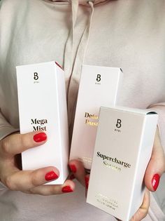 the woman is holding two boxes with different types of perfumes on them, both in their hands