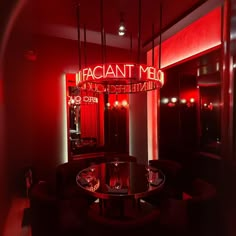 a dimly lit restaurant with red lighting and round tables in the center, surrounded by black chairs