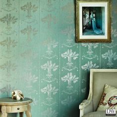 a chair and table in front of a wallpapered room with a painting on the wall