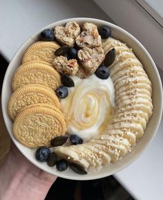 a white bowl filled with cookies, blueberries and banana slices on top of it