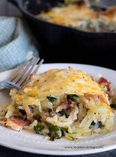 a white plate topped with lasagna covered in cheese and vegetables next to a skillet