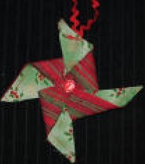 an origami christmas star hanging from a string on a black background with red and green decorations