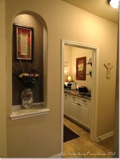 a vase filled with flowers sitting on top of a white shelf next to a doorway