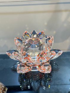 a clear crystal flower on top of a glass table with other items around it and a mirror behind it