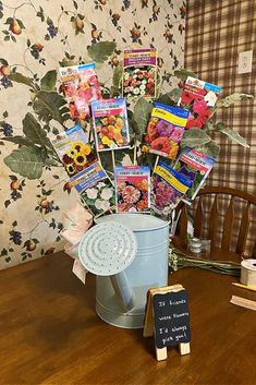 there is a bucket full of flowers and cards on the table next to a chalkboard