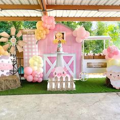 a pink and white farm themed birthday party with balloons, hay bales, sheeps and pigs