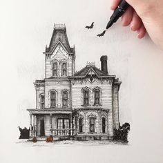 a drawing of a house with bats flying in the air above it and a hand holding a marker