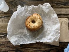 a bagel sitting on top of a piece of wax paper next to a cup of coffee