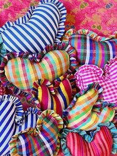 many colorful heart shaped pillows are stacked on top of each other