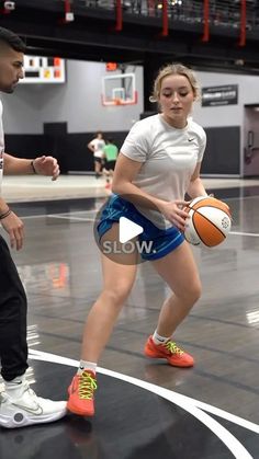 two people are playing basketball on an indoor court with one person holding a ball and the other standing in front of him