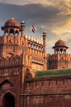 an old brick building with two towers and a flag on it's roof in india