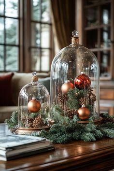 two glass domes with christmas decorations under them sitting on a table next to a book