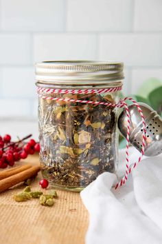 a glass jar filled with spices next to cinnamon sticks and peppercorst on a table