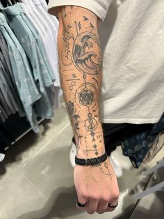 a man's arm with tattoos on it in front of a store display case