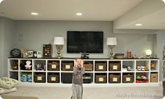 a young boy standing in front of a tv on top of a white entertainment center