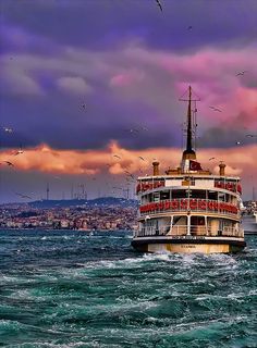 a large boat floating on top of a body of water under a colorful cloudy sky