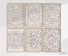 four white and beige wall art pieces with intricate designs on them, hanging in an empty room