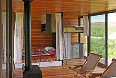 a bedroom with wooden walls and flooring next to a window that has sliding glass doors