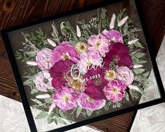 some pink flowers and green leaves on a wooden table with the word thank you written in cursive writing