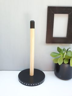 a black and white vase with a wooden stick in it next to a potted plant