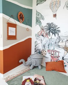 a child's room with an elephant and giraffe mural on the wall