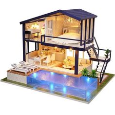 a doll house with a pool and furniture in front of it, all lit up at night