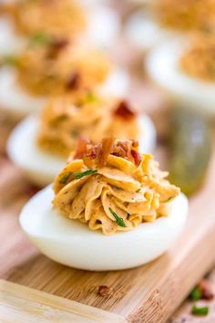 deviled eggs stuffed with bacon and cheese on a cutting board