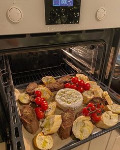 an open oven with bread and tomatoes in it