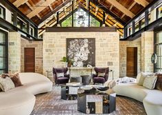 a living room filled with lots of furniture next to a tall ceiling covered in windows