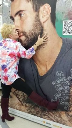 a man holding a small child in front of a large poster with the image of a bearded man on it