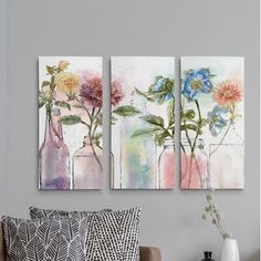 three vases with flowers in them are hanging on the wall next to a couch