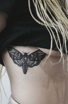 a woman's stomach with a moth tattoo on her lower body and the bottom part of her abdomen