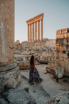 a woman standing in front of some ruins