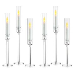 six candles are lined up in different sizes and shapes, each with a yellow light