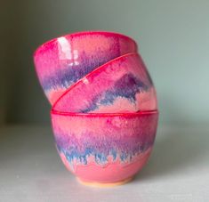 two pink and blue bowls sitting next to each other on a white counter top,