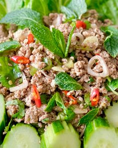 a bowl filled with cucumbers and meat on top of lettuce leaves