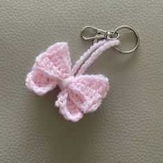 a pink crocheted bow keychain on a leather surface