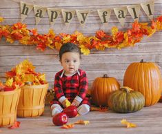 a little boy sitting on the floor in front of some pumpkins and other decorations