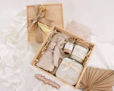 two small boxes with candles and napkins in them on a white sheeted surface