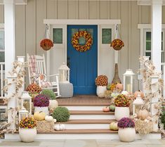 a front porch decorated for fall with pumpkins and wreaths