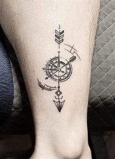 a black and white compass tattoo on the ankle, with an arrow in the center