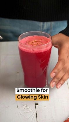 a person holding a glass with some liquid in it and the text smoothie for glowing skin