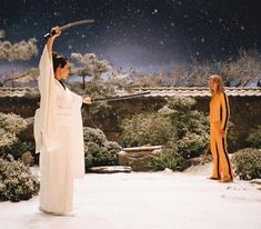 two women dressed in traditional japanese clothing are holding swords and looking at snow falling on the ground