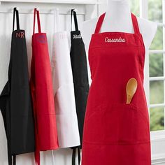 an apron hanging on the wall next to other aprons and cooking utensils