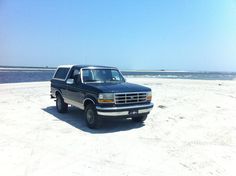 a black truck parked on top of a sandy beach