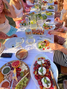 a group of women sitting at a table with plates of food on it and drinks